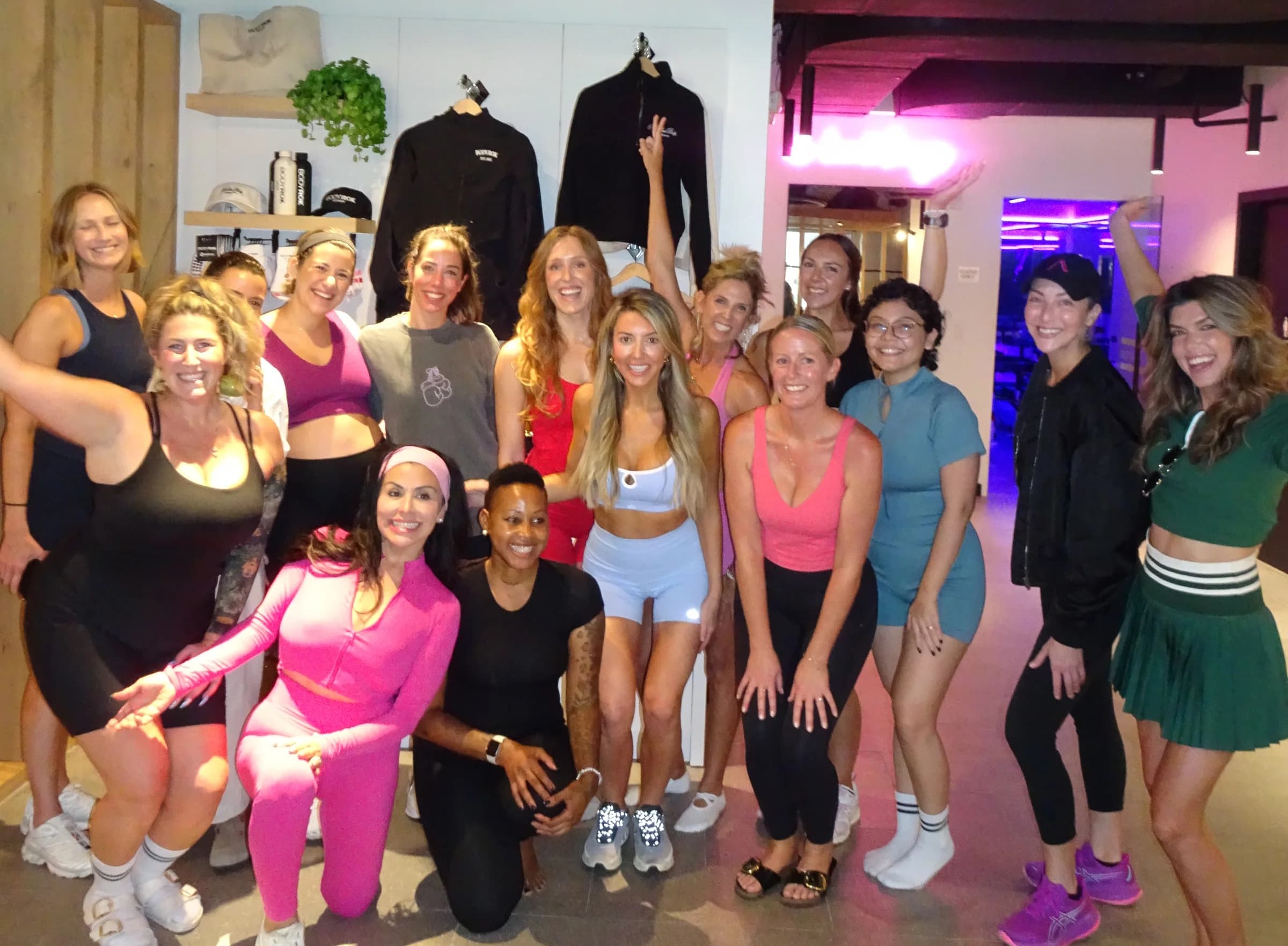A group of women in colorful workout clothes smiling together after a fitness class.