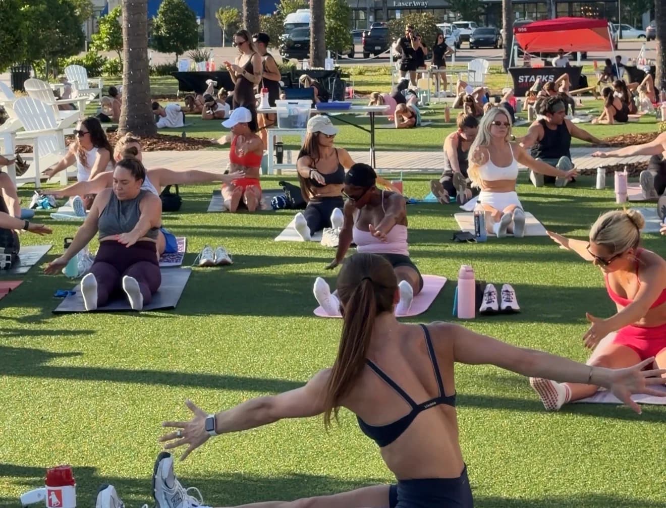 People stretching on exercise mats during an outdoor group fitness class.