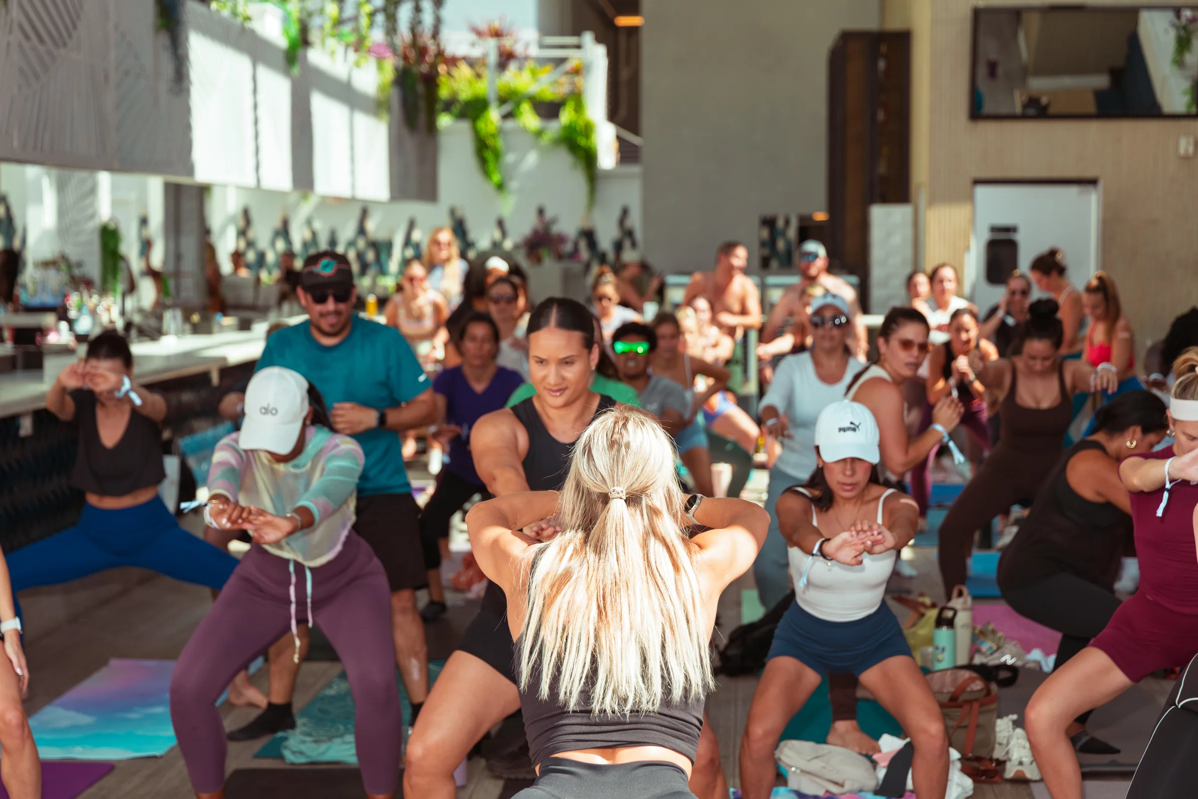 A fitness instructor leading a crowded indoor exercise class.
